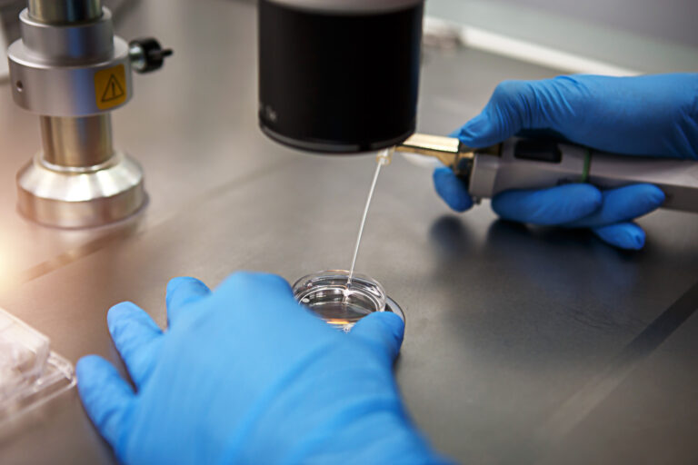 Hands of a scientist in the laboratory with a test tube and a mi